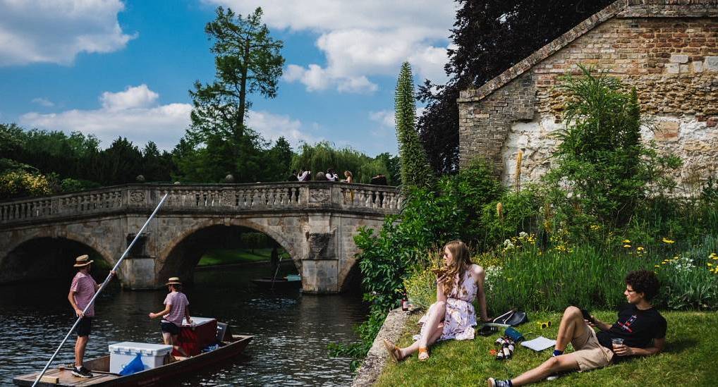 Traditional punt boats gliding down the River Cam past Clare Bridge, scenic historic setting for a Cambridge hen do.