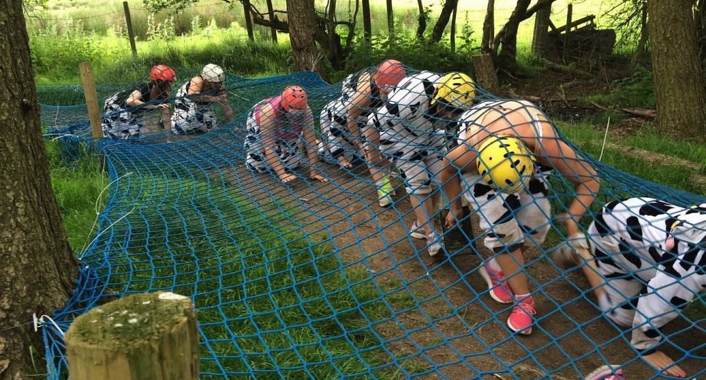 Hen party in fancy dress tackling the scramble net on an Assault Course