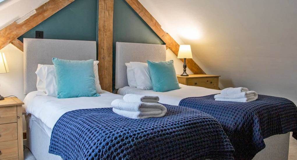 Cosy twin bedroom with exposed beams at Lathkill Escape, part of our luxury Peak District hen cottages.