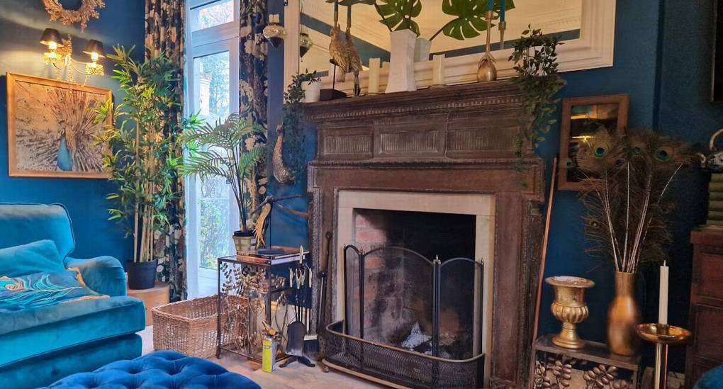A close-up of the elegant open fireplace in the lounge at The Sash House, a focal point for the room with intricate wood carvings and unique decor.