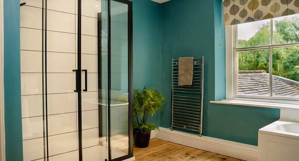 Newly refurbished ensuite walk in shower room at the Wye House displaying bright turquoise walls and large window. 