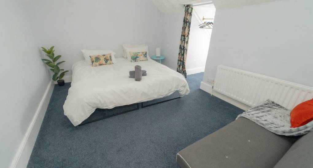 A bright and flexible twin bedroom at Tranquil Escape featuring zip-and-link beds, tropical leaf cushions, and an additional sofa bed for group comfort near Newcastle.