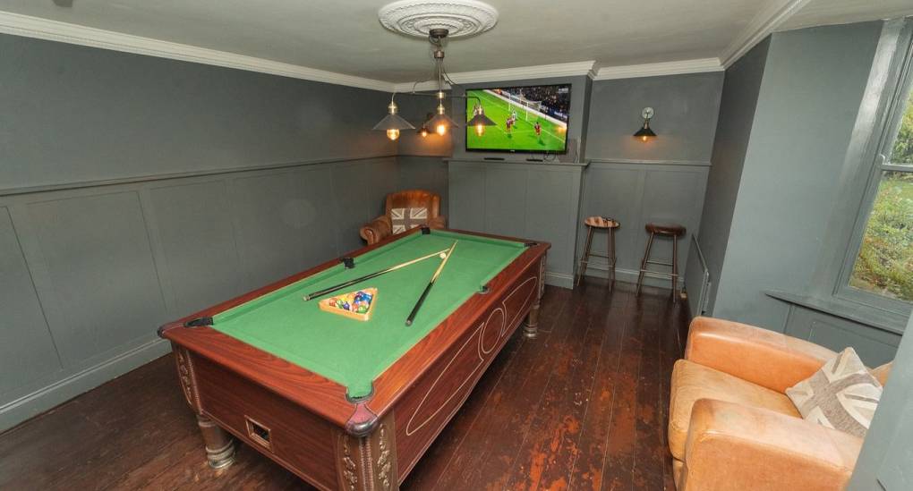 The private games room at Tranquil Escape, a rural Newcastle hen do house, featuring a full-size pool table, wall-mounted TV with Sky Sports, and comfortable leather armchairs for group socializing.