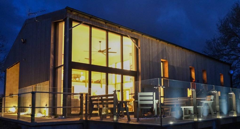 Illuminated exterior of Tree View converted barn Party House at night