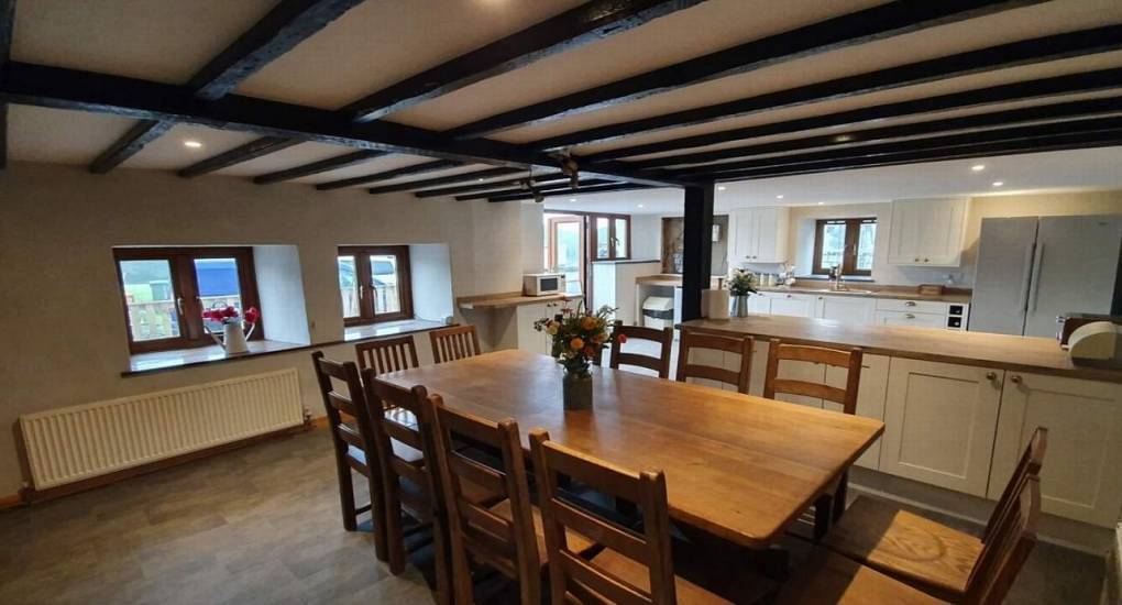 The rustic beam ceiling dining room and kitchen at Devon Hideaway, a rural North Devon hen cottage for 12.